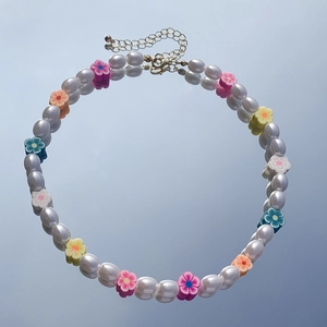 Dettaglio collana di perle con fiori colorati in argilla e chiusura a moschettone oro