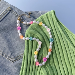 Dettaglio di perline a margherita colorate e perle barocche su sfondo denim