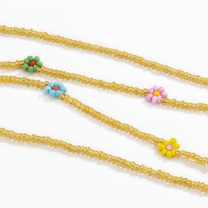Detail of colorful beaded waist chain featuring small daisies and golden glass beads