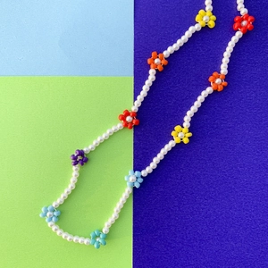 Dettaglio macro di perline a margherita colorate e perle barocche su una collana choker