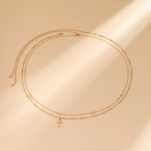 Detailed view of a gold double-layer waist chain featuring crystals and a cross pendant