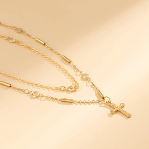 Detailed view of a layered gold waist chain featuring a diamond-encrusted cross pendant