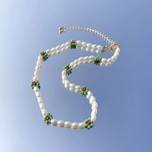 Dettaglio di collana di perle barocche con motivi a fiori di perline e chiusura a moschettone