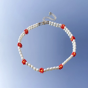 Dettaglio della collana a margherita con perle barocche e accenti floreali colorati su blu
