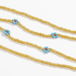 Detailed close-up of handmade Bohemian daisy waist chain with yellow and blue beads