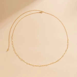 Elegant gold waist chain with rhinestones and geometric metal charms on beige background