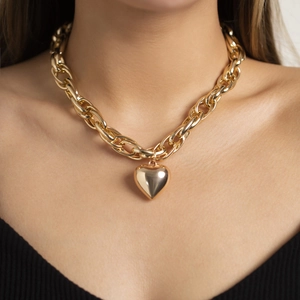 Collana a catena grossa dorata con ciondolo a cuore lucido indossata su modella