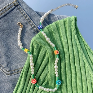 Dettaglio della collana con perle finte, ciondoli a margherita e chiusura dorata