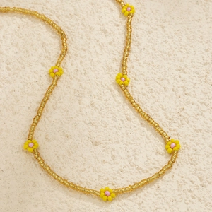 Detail of colorful seed bead waist chain with yellow and pink resin flower accents