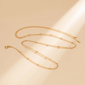 Detailed view of layered gold chain necklace featuring floral pendants and bead accents