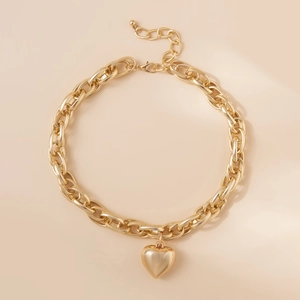 Dettaglio di una collana a catena dorata spessa con un ciondolo a cuore e chiusura