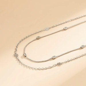 Detail of silver double-layered chain with hollow flower charm and polished metal beads