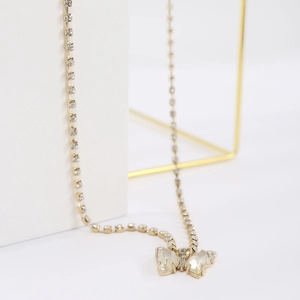 Detail of gold-tone butterfly pendant with shimmering crystals on a chic double chain