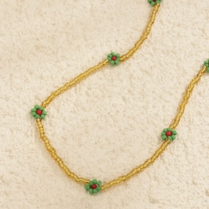Detail of handmade daisy body chain with gold translucent beads and floral patterns