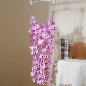 Detailed view of pink star sequins and metal tassel chains on a stylish body chain