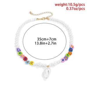 Dettaglio di collana boho con perle bianche e perline a forma di fiori colorati
