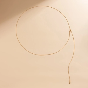 Macro shot of minimalist gold double layer body chain with round metal pendant