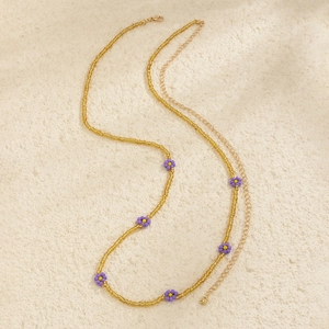 Detail of yellow beaded body chain featuring handcrafted purple floral daisy accents