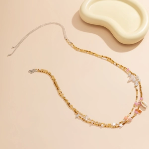 Dettaglio catena in vita boho con conchiglie, cristalli rosa e perline colorate
