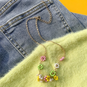 Dettaglio della collana di perline colorate a margherita con perle barocche su tessuto
