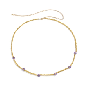 Detail of bohemian waist chain with purple daisy beads and golden lobster clasp closure