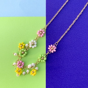 Dettaglio di una collana a catena dorata con margherite di perline colorate e perle