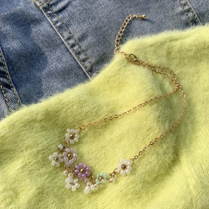 Dettaglio della collana colorata con margherite di perline su denim e maglia