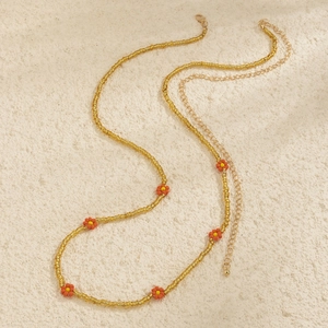 Detail of handmade seed bead daisy chain with orange flowers and gold lobster clasp