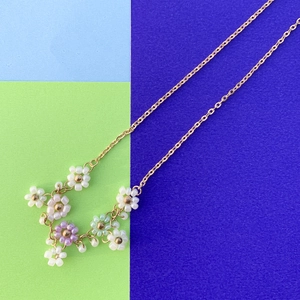 Dettaglio di fiori di margherita colorati in perline fatti a mano su una catena dorata