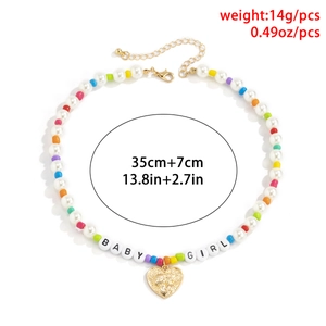 Dettaglio collana con perline colorate, lettere BABY GIRL e ciondolo a cuore dorato lucido