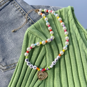 Dettaglio della collana di perline colorate con lettere BABY GIRL e ciondolo a cuore