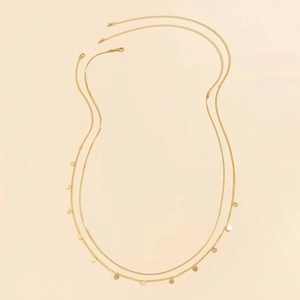 Detail of golden double-layer chain with flat snake bone link and mini round sequins charms