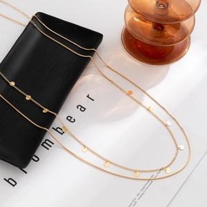 Detail of a gold double-layer chain waist link with small polished round disc pendants