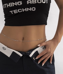 Close-up of a silver geometric waist chain with crystal charms on a female model