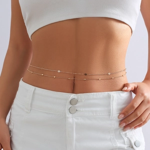 Close-up of double-layer gold waist chain with delicate floral charms on a female model