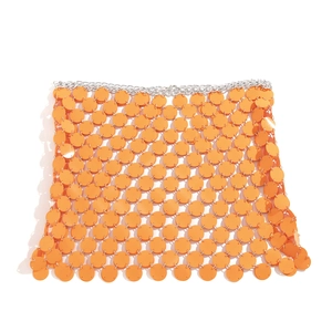 Detail eines sexy orangefarbenen Pailletten-Body-Chain-Rocks mit Metallringen auf Weiß