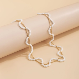 Detail der gewebten weißen Perlen und goldener Metallkette in eleganter Muscheloptik
