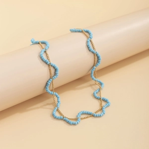Detail einer böhmischen himmelblauen Perlenkette und goldener Gliederkette auf Dekostand