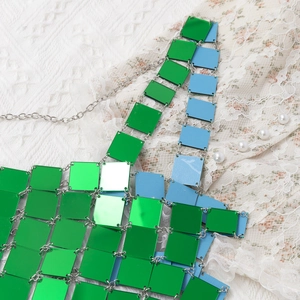 Detailed view of green and blue metallic sequins connected by silver chains for body jewelry