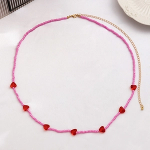 Detailaufnahme der rosa Perlen-Taillenkette mit roten Herzanhängern und Goldverschluss