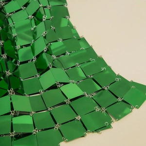 Close-up of emerald green mirrored square tiles with silver metal ring connections