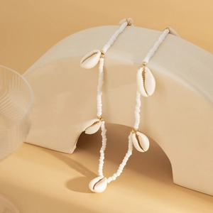 Detail of bohemian beaded waist chain with natural white shells and gold metal accents
