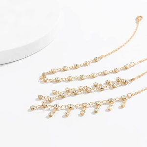 Macro shot of gold-plated body chain featuring delicate rhinestones and fringe tassels