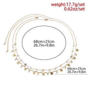 Détail d'une chaîne de corps dorée multicouche avec pendentifs papillon et strass