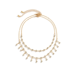 Detail view of double-layer gold waist chain with rhinestones and tassel fringe on white background
