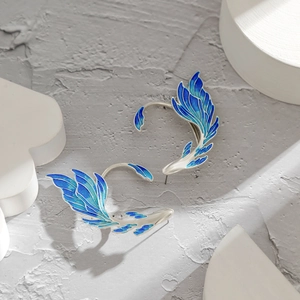 Detailed macro of silver ear cuffs with blue enamel butterfly wings and glitter finish