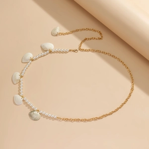 Detail view of gold waist chain featuring white seed beads and natural shell pendants