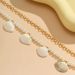 Close-up of double-layered body chain with pearls and natural golden shell charms