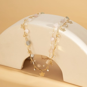 Détail de la chaîne de corps dorée avec pendentif papillon et perles de quartz rose
