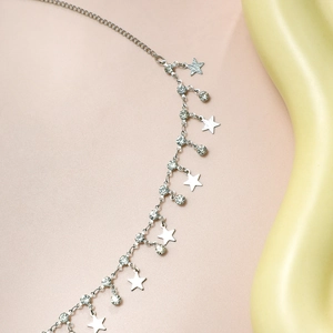 Detail of silver body chain with polished star pendants and sparkling crystal accents